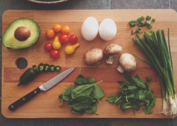 Planches à découper avec plusieurs aliments (œufs, avocats, tomates, etc.) dessus, on voit aussi un couteau déposé sur la planche
