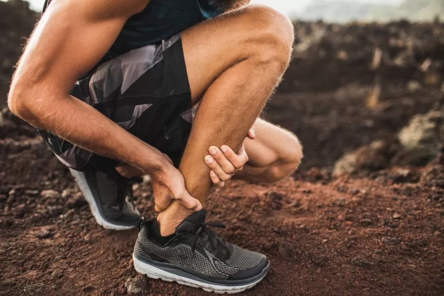 Un coureur à l'arrêt, semble avoir mal au tendon d'Achille