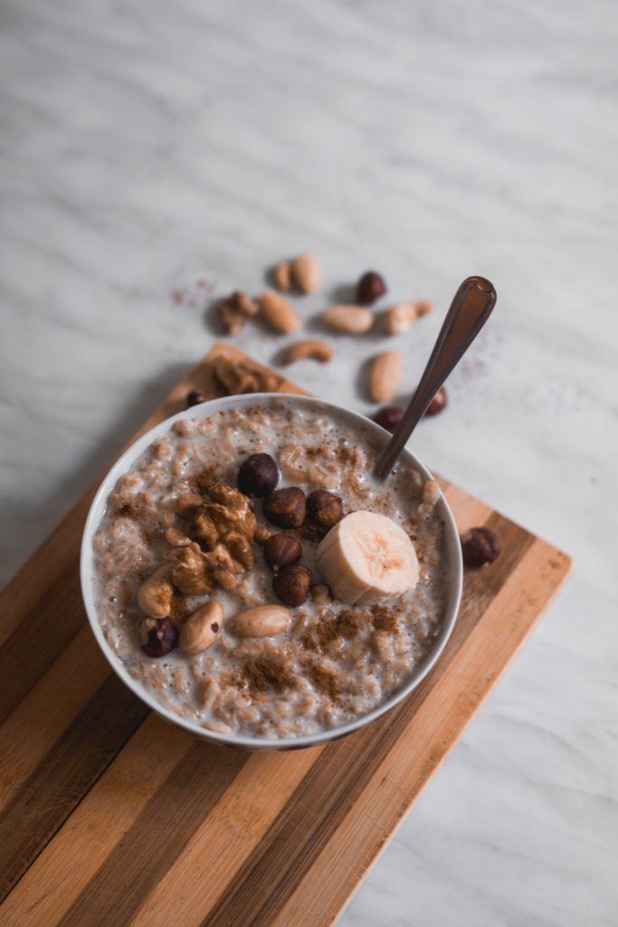 Bolle sur une plache à découper contenant un porridge agrémenté de noisettes