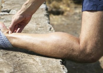 Personne avec le tibia posé sur un muret, la personne a mal au tendon d'Achille