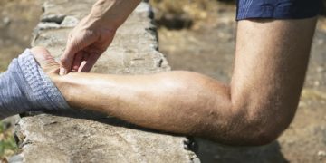 Personne avec le tibia posé sur un muret, la personne a mal au tendon d'Achille