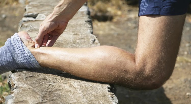 Personne avec le tibia posé sur un muret, la personne a mal au tendon d'Achille