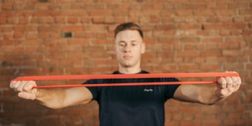 Personne tendant une bande élastique de musculation tendu devant lui