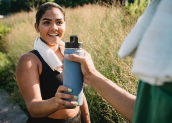 Quelqu'un qui donne une gourde à une femme qui semble faire du sport