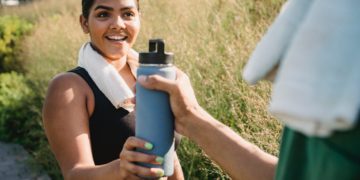 Quelqu'un qui donne une gourde à une femme qui semble faire du sport