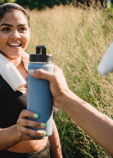 Quelqu'un qui donne une gourde à une femme qui semble faire du sport