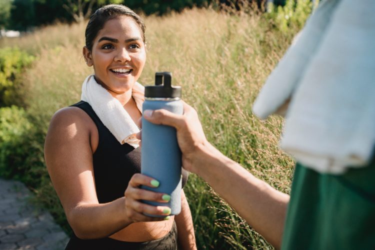 Quelqu'un qui donne une gourde à une femme qui semble faire du sport