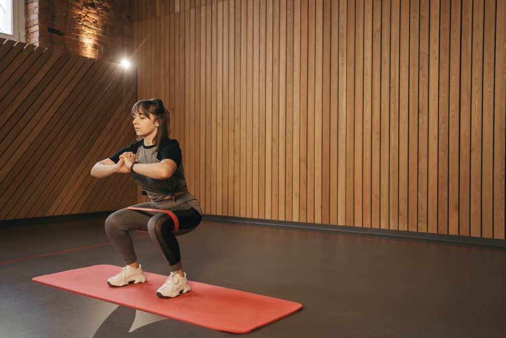 Femme faisant un squat avec une bande élastique de musculation entre les genoux