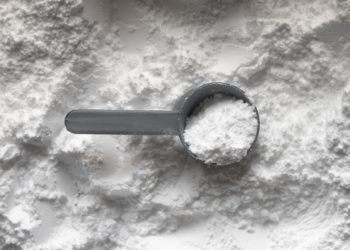 Poudre de Whey, sur laquelle une cuillère doseur est posée