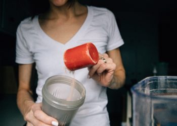 Femme qui remplit un shaker d'une poudre, probablement de la BCAA