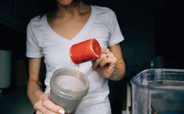 Femme qui remplit un shaker d'une poudre, probablement de la BCAA